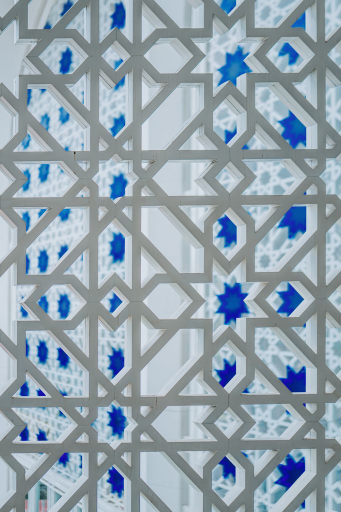 Close-up of intricate geometric patterns and blue glass in Shah Alam Mosque, Malaysia.